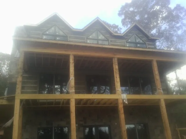 Dormers and porch framing on a large log home under construction — Roof Coating work by our crew in Bolivar